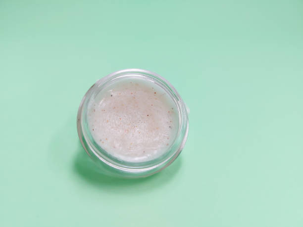 A small jar of homemade lip scrub sits on a mint green background, illustrating DIY kitchen beauty recipes.